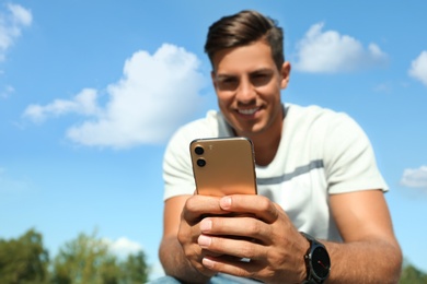 Photo of Handsome man using modern mobile phone outdoors, focus on hand