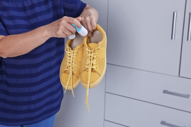 Woman putting capsule shoe freshener in footwear indoors, closeup