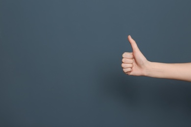 Young woman showing thumb sign on color background. Space for text