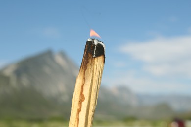 Photo of Burning palo santo stick in high mountains, closeup