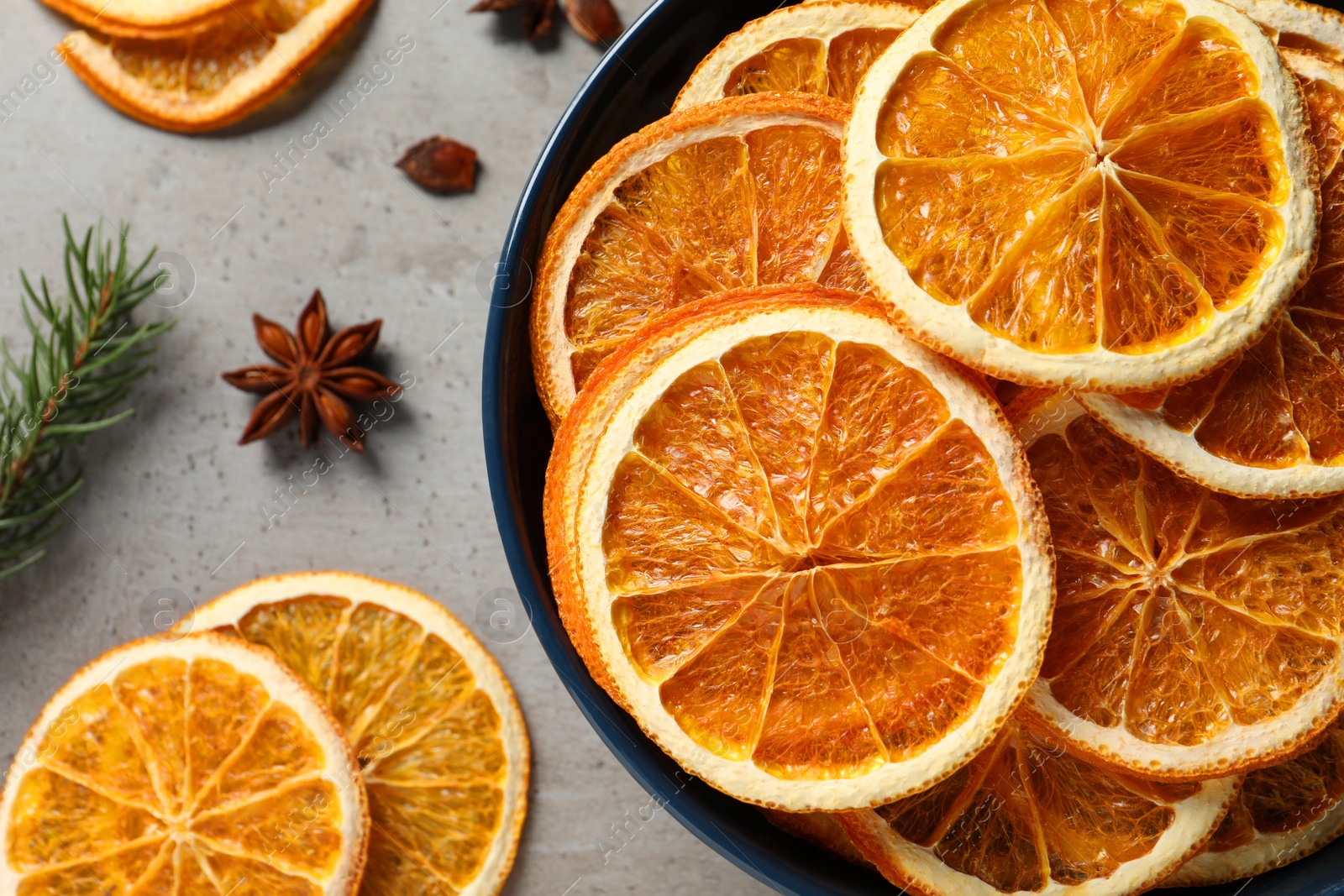 Photo of Dry orange slices and anise stars on grey table, flat lay