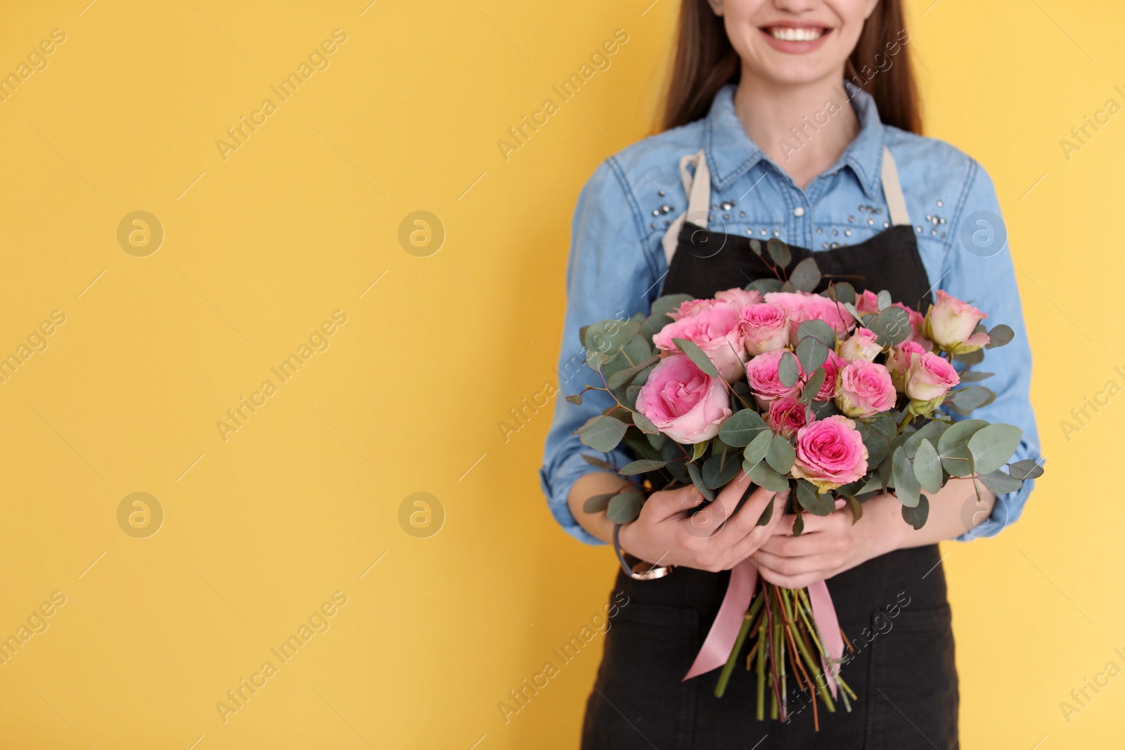 Photo of Female florist holding bouquet of beautiful flowers on color background