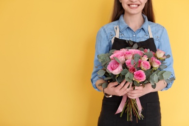 Female florist holding bouquet of beautiful flowers on color background