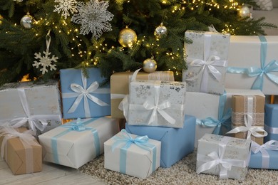 Many gift boxes under beautiful Christmas tree on floor at home