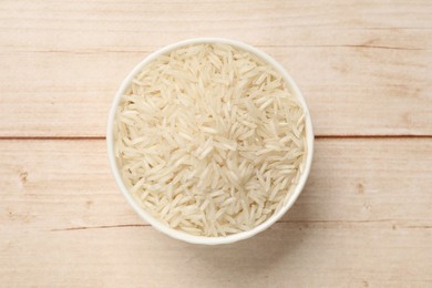 Photo of Raw basmati rice in bowl on white wooden table, top view