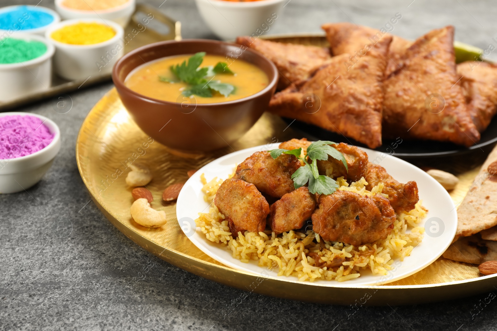 Photo of Traditional Indian food and color powders on grey table, closeup. Holi festival celebration