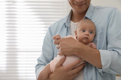 Photo of Happy father holding his cute little baby at home, closeup. Space for text