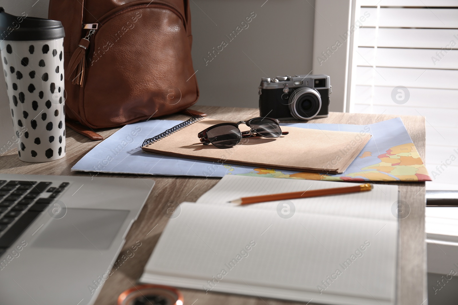 Photo of Notebook and travel accessories on wooden table. Planning summer vacation trip