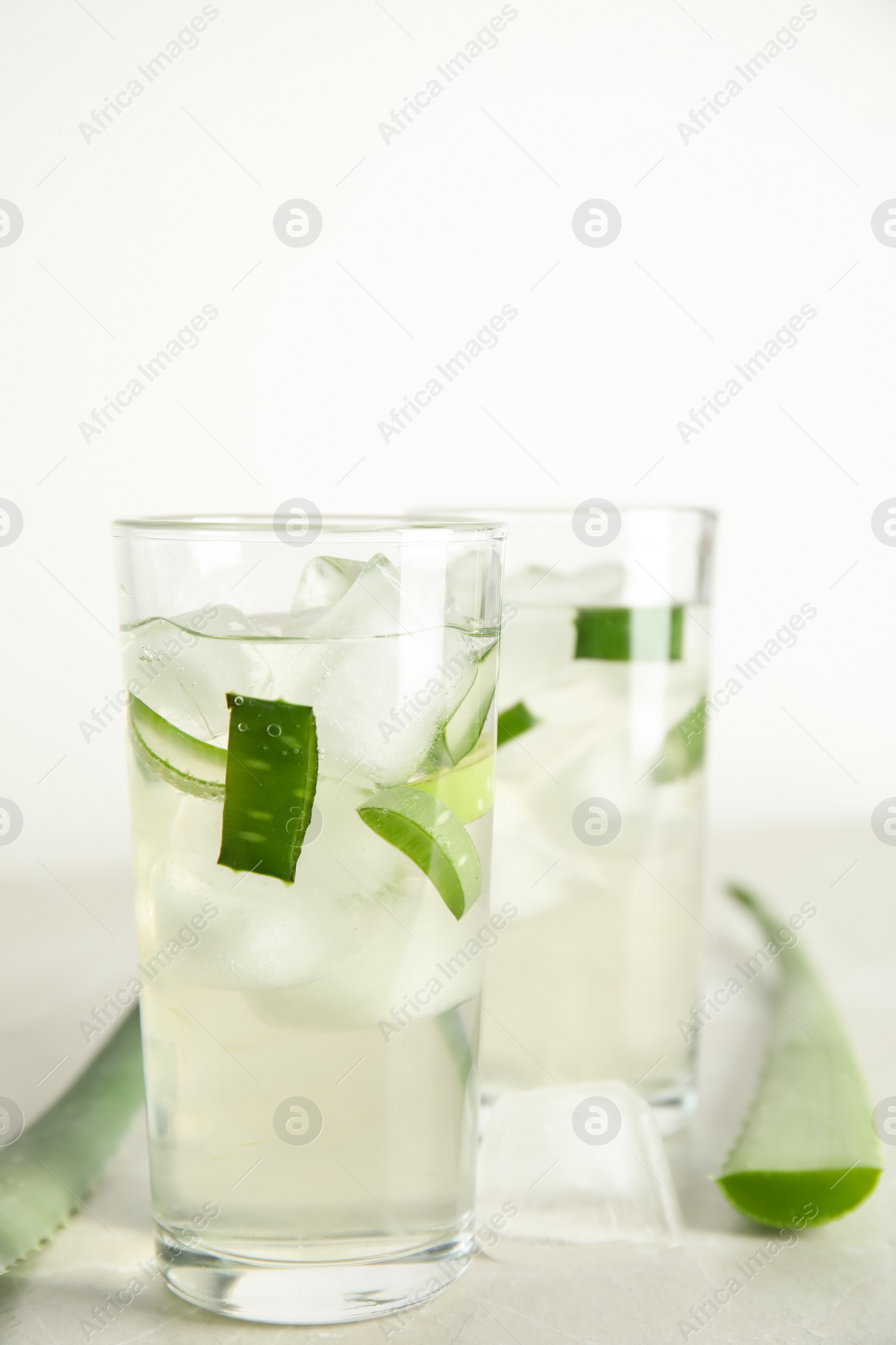 Photo of Fresh aloe drink in glasses and leaves on light table, closeup