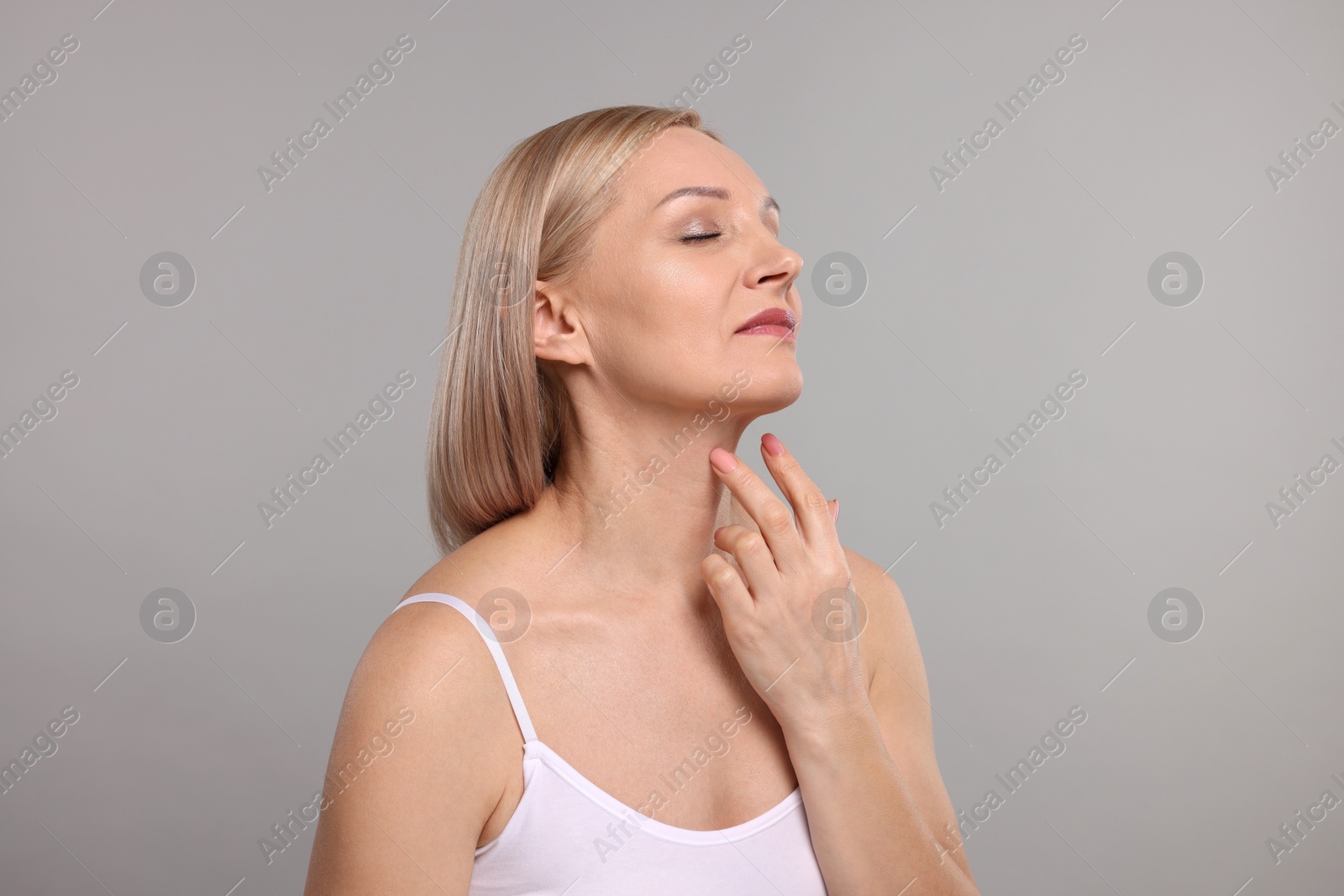 Photo of Beautiful woman touching her neck on grey background