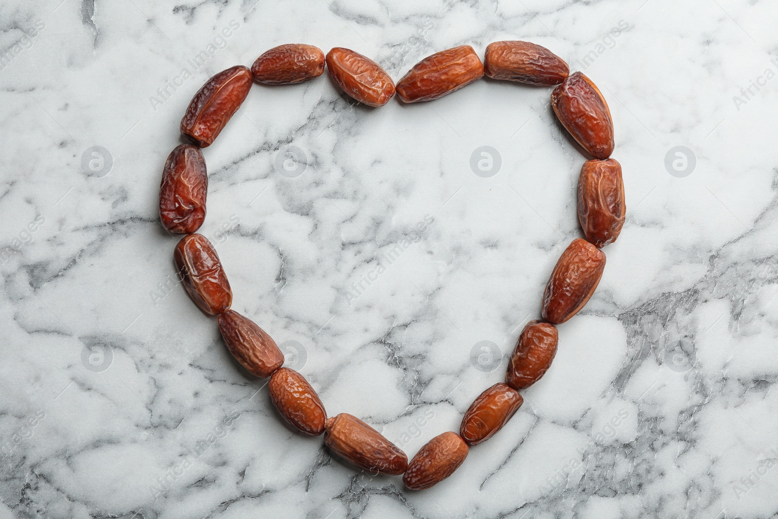 Photo of Frame made of sweet dried date fruits on marble background, top view with space for text