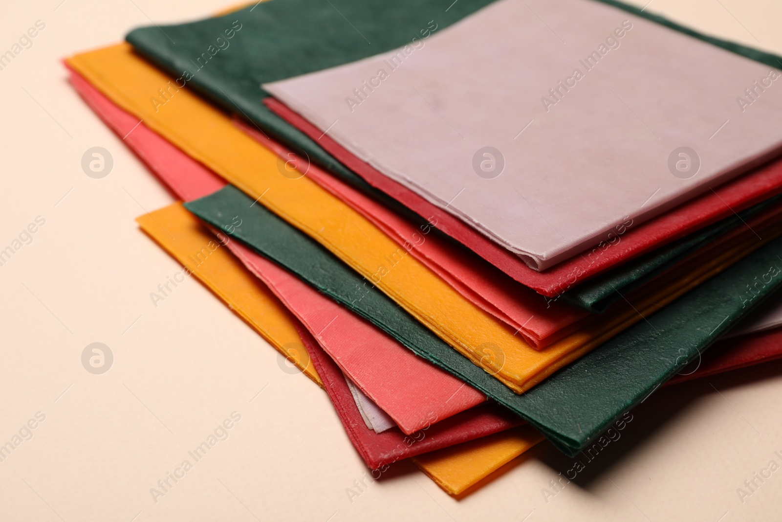 Photo of Colorful reusable beeswax food wraps on beige background, closeup