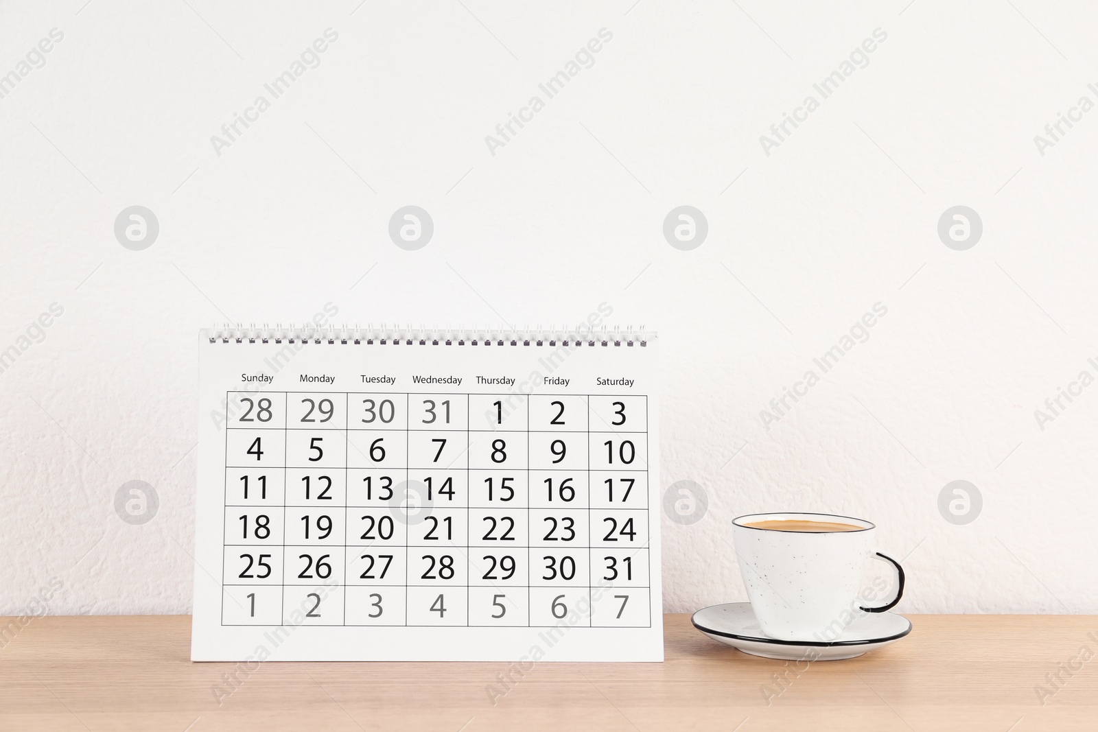 Photo of Calendar and cup of coffee on wooden table