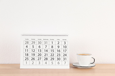 Photo of Calendar and cup of coffee on wooden table