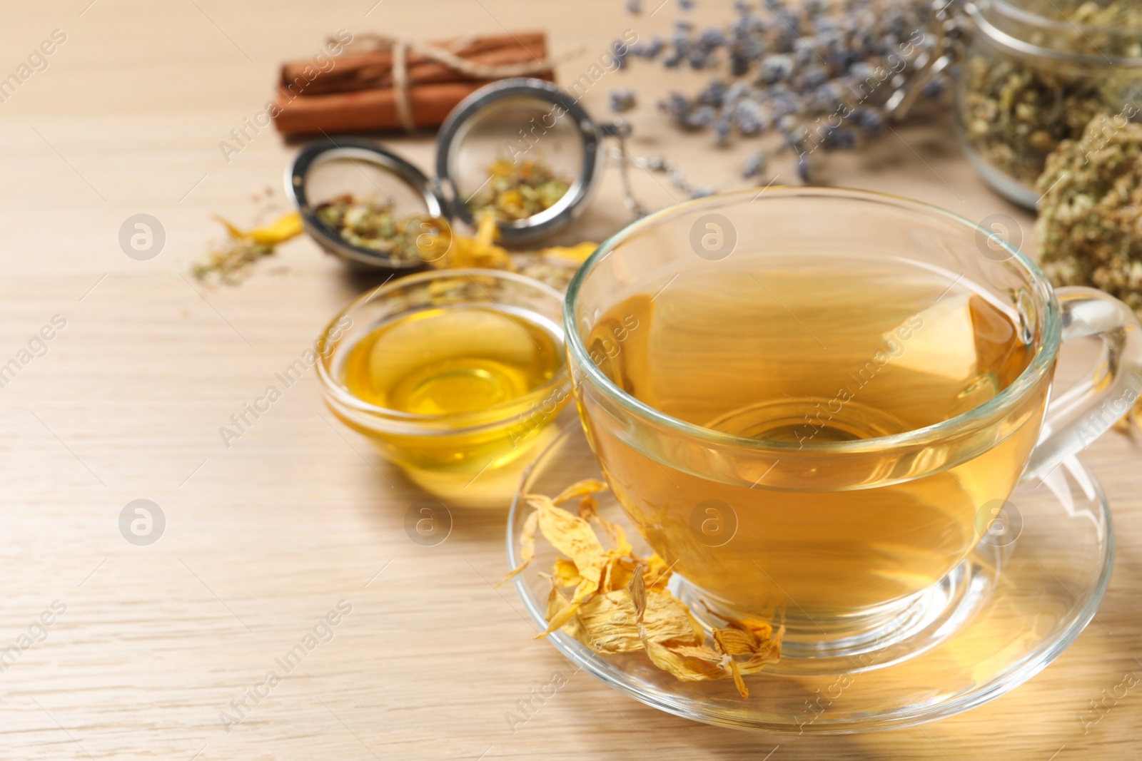 Photo of Freshly brewed tea and dried herbs on wooden table. Space for text