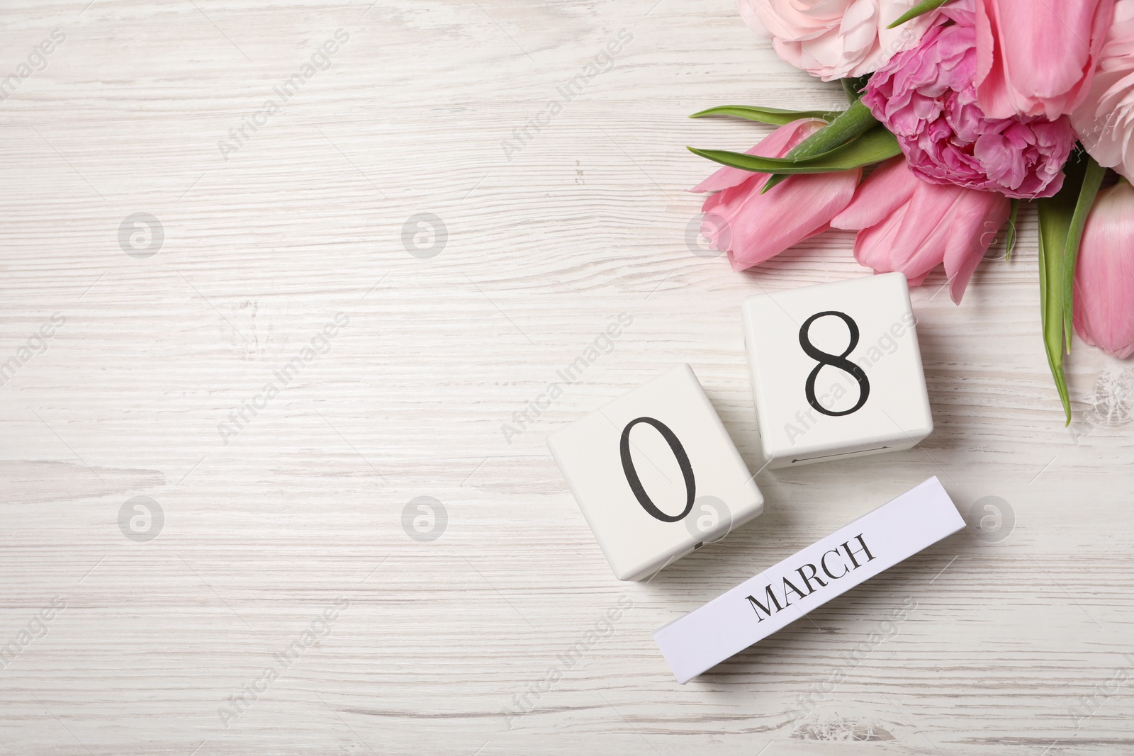 Photo of International Women's day - 8th of March. Block calendar and beautiful flowers on white wooden table, flat lay. Space for text