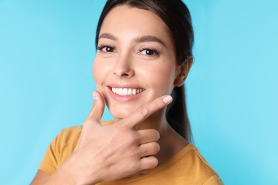 Young woman with healthy teeth on color background