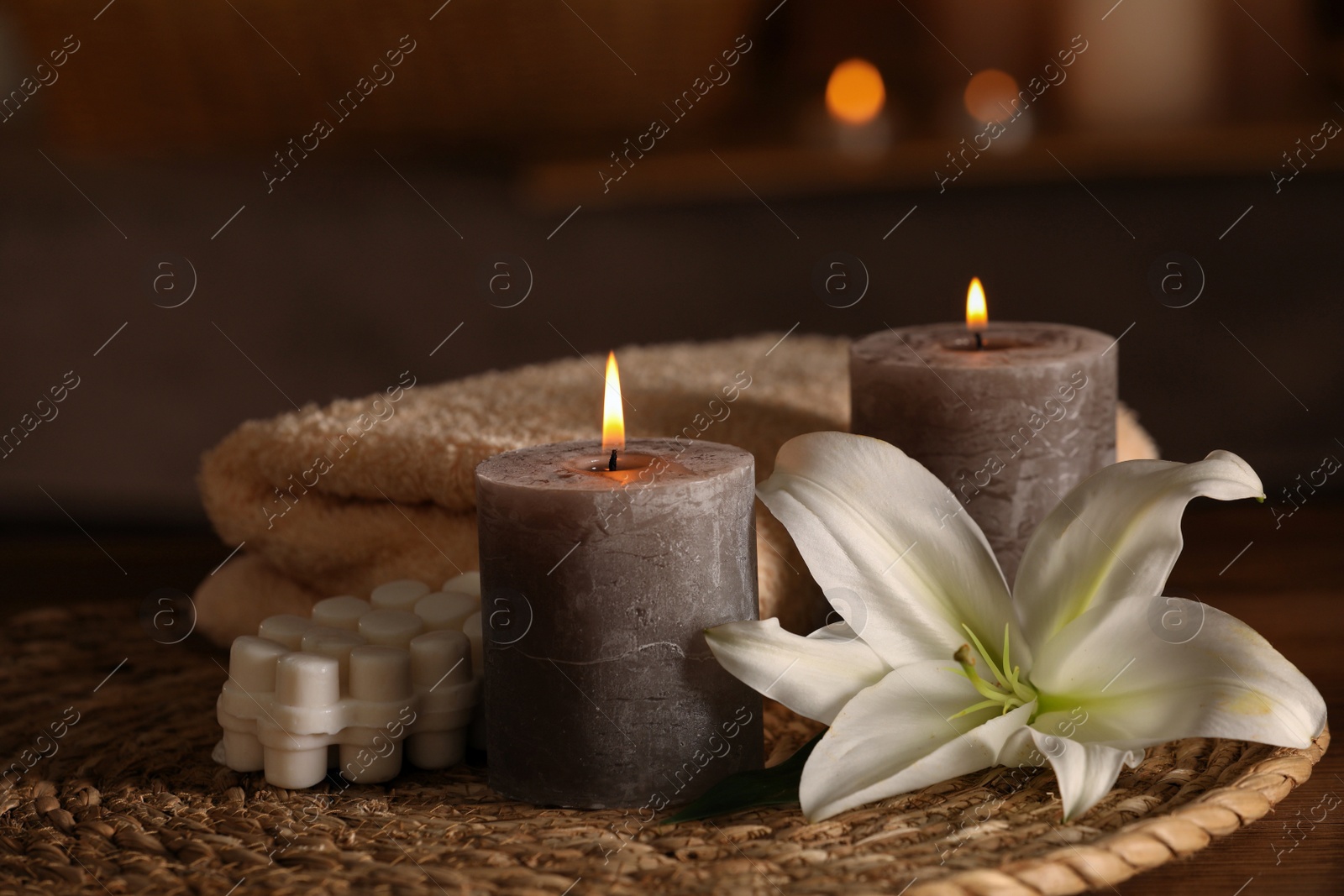 Photo of Spa composition with burning candles, lily flower and towels on wooden table in wellness center