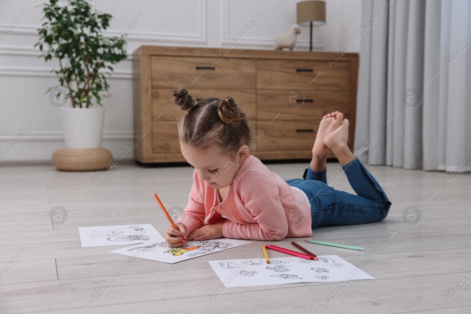 Photo of Cute little girl coloring on warm floor at home. Heating system