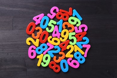 Photo of Colorful numbers on dark wooden school desk, top view