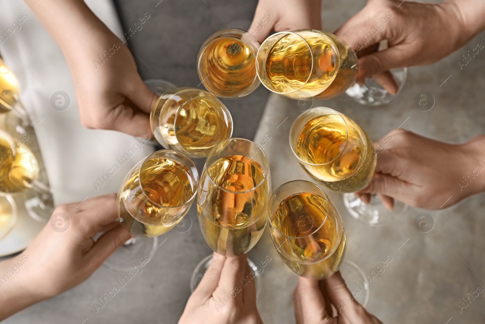 Photo of People clinking glasses with champagne over table, top view