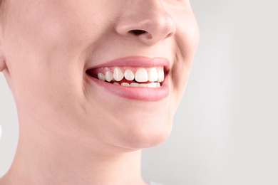 Young woman with healthy teeth smiling on white background, closeup