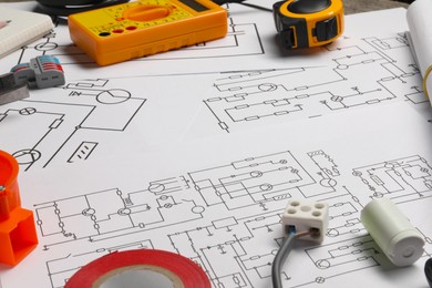 Photo of Digital multimeter and other electrician's equipment on wiring diagrams