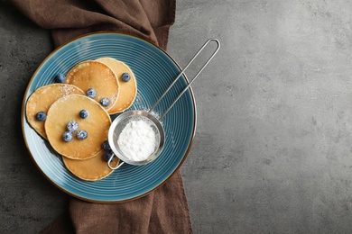 Photo of Plate with pancakes, berries and sugar powder on grey background, top view