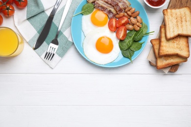 Photo of Tasty breakfast with fried eggs, bacon and toasts served on white wooden table, flat lay. Space for text