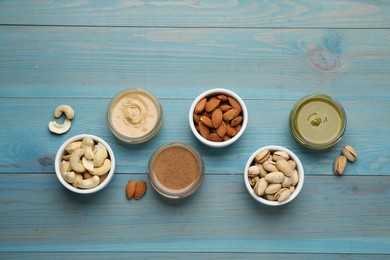 Photo of Different types of delicious nut butters and ingredients on light blue wooden table, flat lay