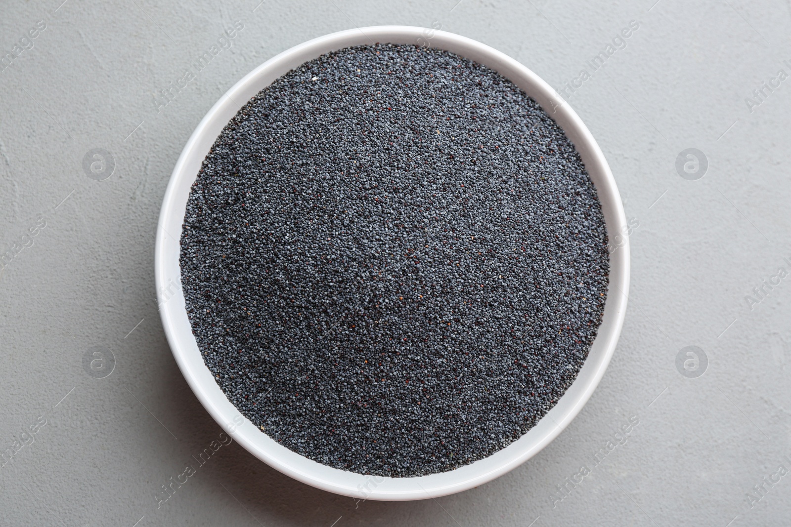 Photo of Poppy seeds in bowl on grey table, top view