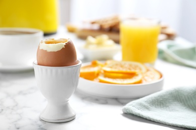 Photo of Cup with soft boiled egg on marble table, space for text. Healthy breakfast