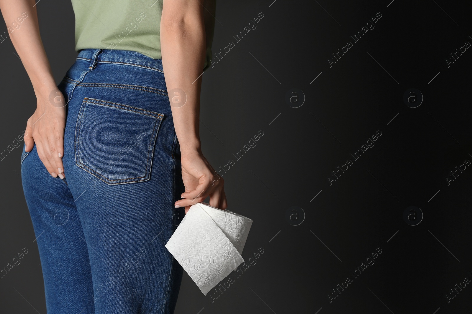 Photo of Woman with toilet paper suffering from hemorrhoid on black background, closeup. Space for text