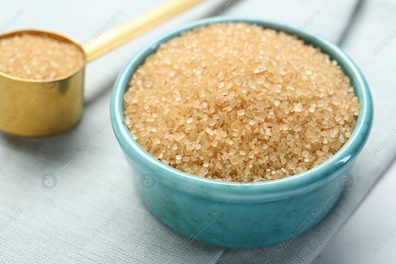 Photo of Brown sugar in bowl and scoop on table, closeup