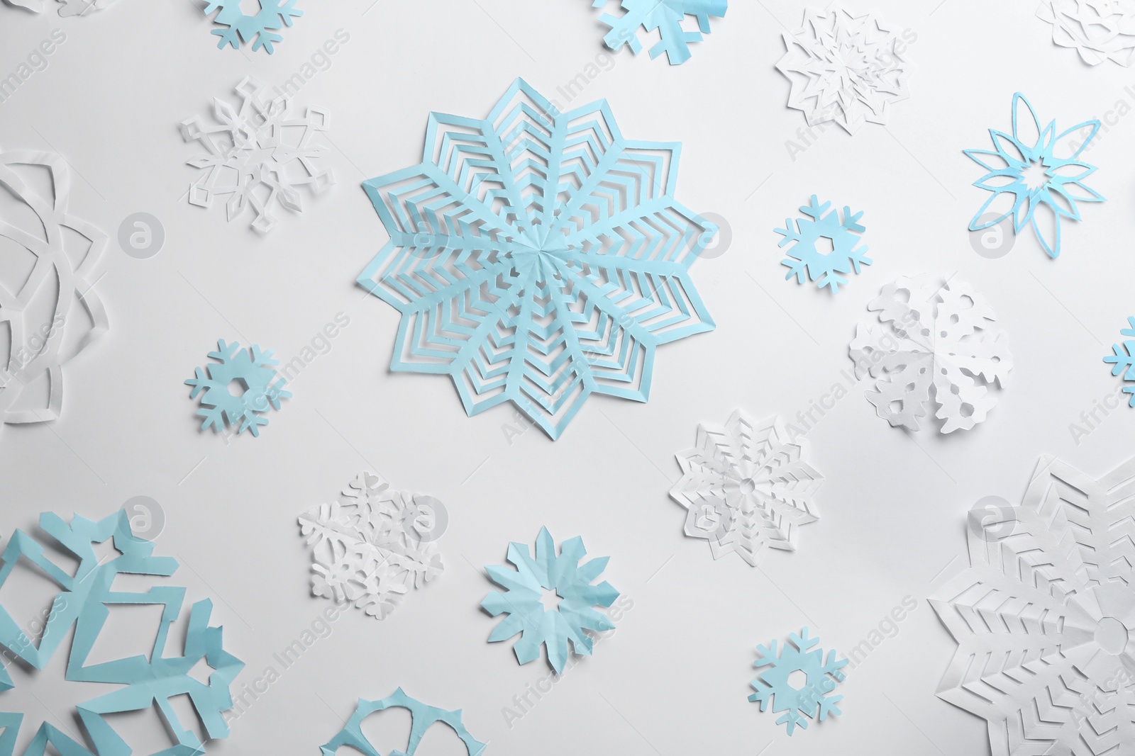 Photo of Many paper snowflakes on white background, flat lay