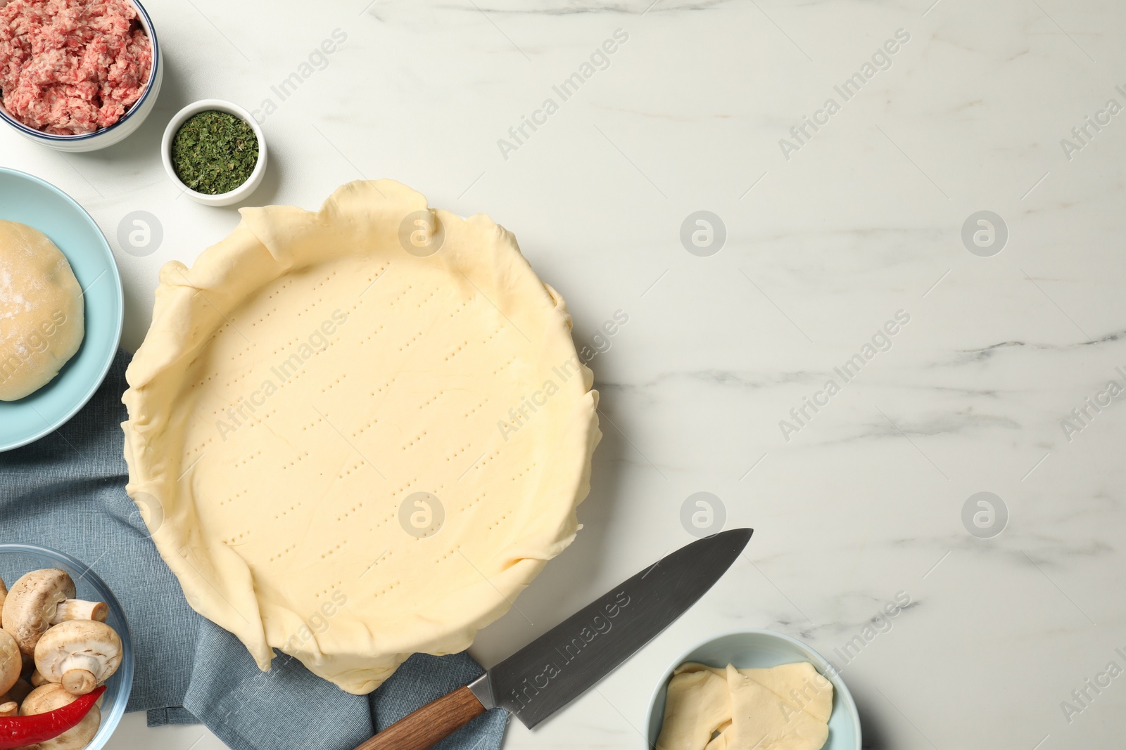 Photo of Flat lay composition with raw dough and ingredients on white marble table, space for text. Baking meat pie
