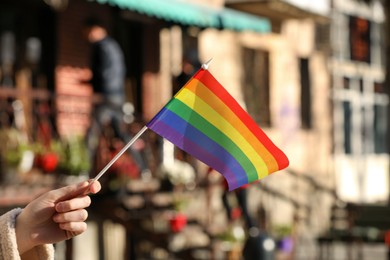 Photo of Woman holding bright LGBT flag on city street, closeup
