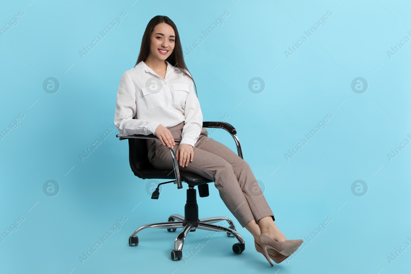 Photo of Young businesswoman sitting in comfortable office chair on turquoise background