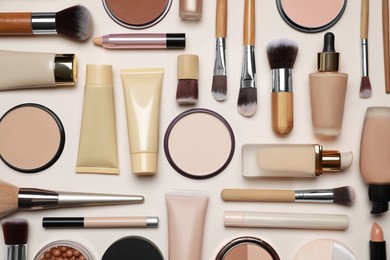 Photo of Face powders and other makeup products on beige background, flat lay
