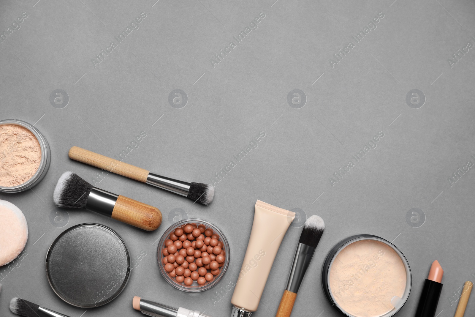 Photo of Face powders and other makeup products on grey background, flat lay. Space for text