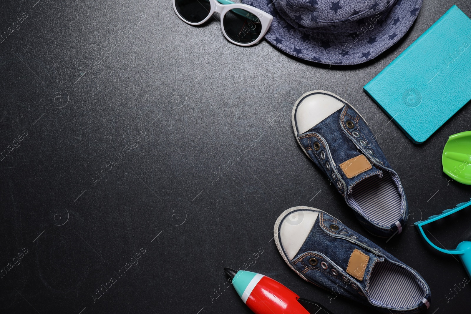 Photo of Flat lay composition with child's shoes on blackboard, space for text. School holidays