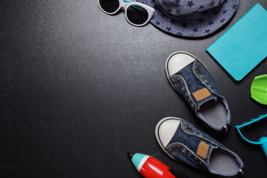 Photo of Flat lay composition with child's shoes on blackboard, space for text. School holidays