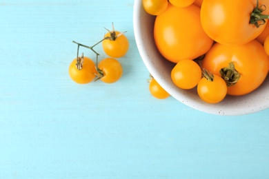 Photo of Ripe yellow tomatoes on light blue wooden table, flat lay