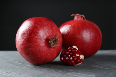 Photo of Ripe pomegranates on table against black background