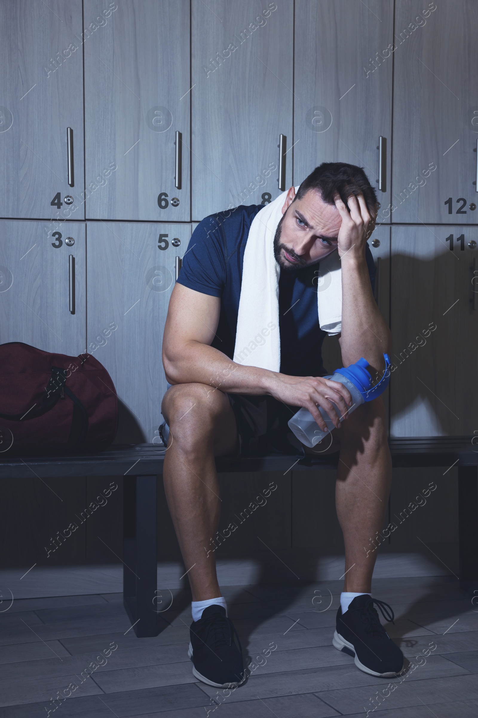 Image of Handsome tired man with shaker in locker room