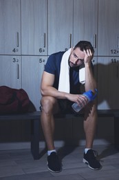 Handsome tired man with shaker in locker room