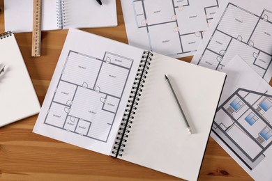 Photo of Sketchbook with construction drawings and pencil on wooden table, flat lay