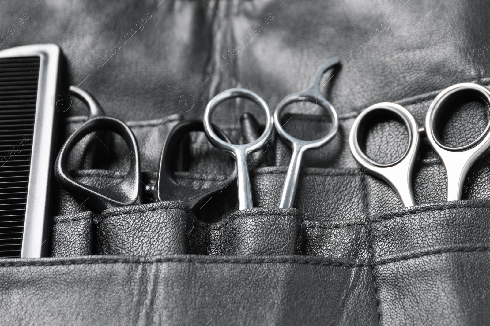 Photo of Hairdresser tools. Professional scissors and comb in leather organizer, closeup