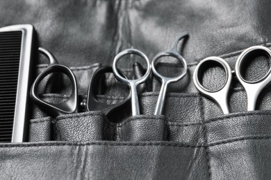 Hairdresser tools. Professional scissors and comb in leather organizer, closeup