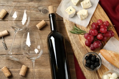 Flat lay composition with red wine and snacks on wooden table